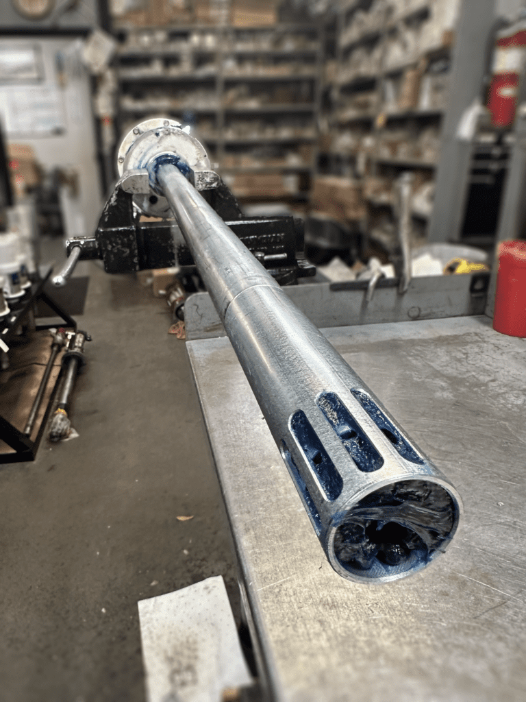 Lateral view of silver grease pump and end pipe with blue grease inside